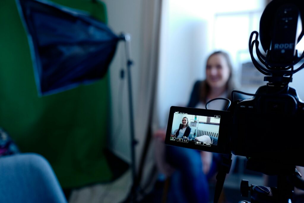 Woman being recorded in a professional studio setup, using video camera and lighting equipment.